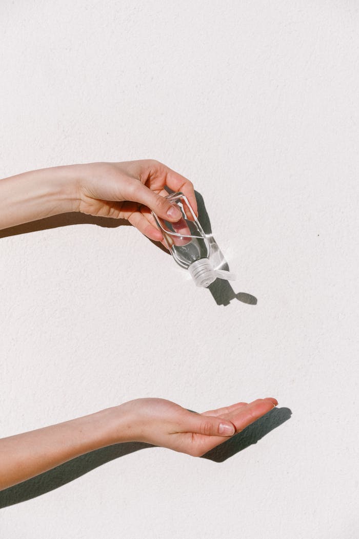 The Art of Drawing Readers In: Your attractive post title goes here Person applying hand sanitizer against white backdrop, emphasizing hygiene and protection.